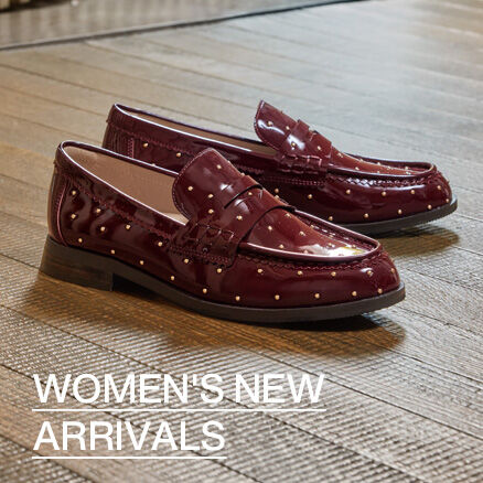 Pair of burgundy patent leather women's loafers with decorative gold studs displayed on a wood floor. Text reads &ldquo;Women's New Arrivals.&rdquo;